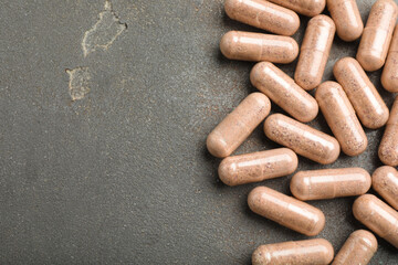 Gelatin capsules on grey table, flat lay. Space for text