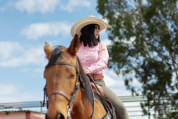 Close up of a beautiful girl riding a horse in a ranch