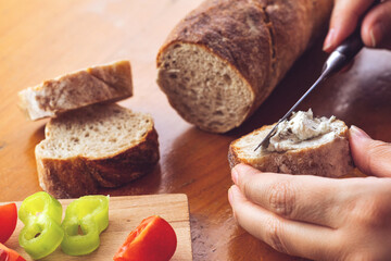 Woman hand spreading basil and parsley cream over bread with knife. Selective focus.	