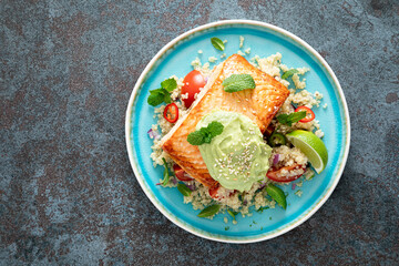 Grilled salmon fillet, quinoa fresh vegetable salad with tomato and avocado guacamole. Top view
