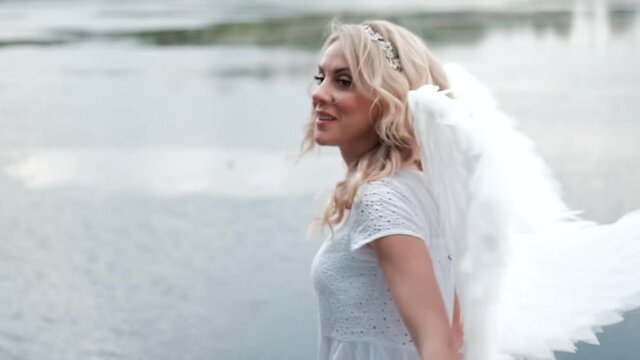 portrait of blonde woman in white dress and white angels wings. good people. heaven, god. paradise angel. slow motion.