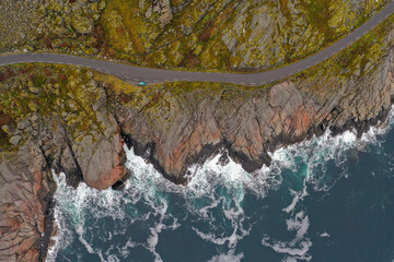 Top down aerial view of Great Ocean Road in Lofoten Norway. Scenic ocean rocky shore with picturesque road among green fields. Big waves and perfect atmoshphere.