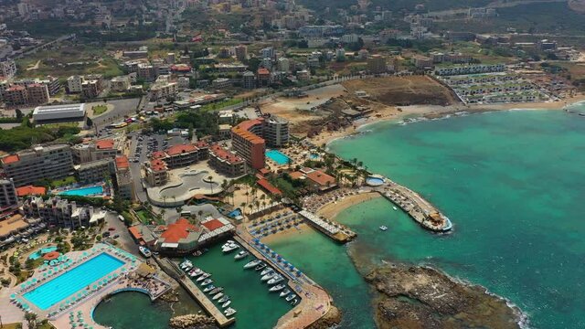Aerial Panning Residential Buildings On Landscape In City, Drone Flying Over Nautical Vessels In Sea - Batroun, Lebanon