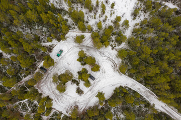 Aerial top down view on green camper van and parking lot. Beautiful forest in winter near Alta in Norway. - obrazy, fototapety, plakaty