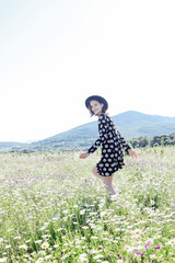 Fototapeta premium a beautiful woman walks through a field of daisies