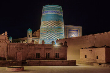 Night view of Khiva, Uzbekistan. Blue minaret of Kalta-Minor is in center. Foreground (in shade, left to right): Muhammad-Rakhim madrasah, Kohna-Ark palace, small building of zindan