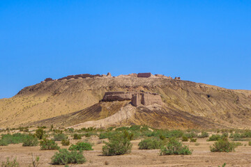 Panorama of desert fortress Ayaz-Kala in middle of spring Kyzyl Kum desert, Uzbekistan. Fortifications were built in 3-4 cent. BC. Main fortress (background) was built on high hill, up to 100 m high