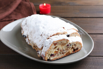 Traditional Christmas Stollen with icing sugar on wooden table