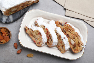 Traditional Christmas Stollen with icing sugar on grey table, flat lay