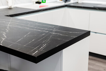 Black countertop in the kitchen with a white furniture - obrazy, fototapety, plakaty