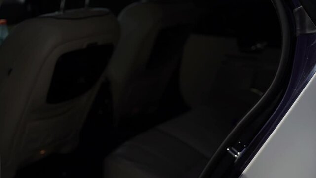 Man in black suit opens car door. Sedan auto driver opening rear door of white luxury limousine vehicle. VIP passenger service.