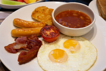 Fried eggs, bacon, sausages, beans, tomatoes for breakfast.