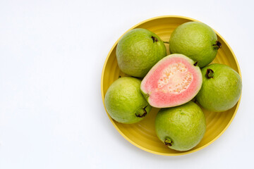Fresh pink guava in yellow plate on white background.