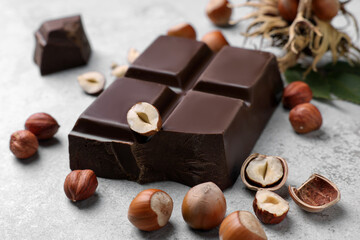 Delicious chocolate and hazelnuts on light table, closeup