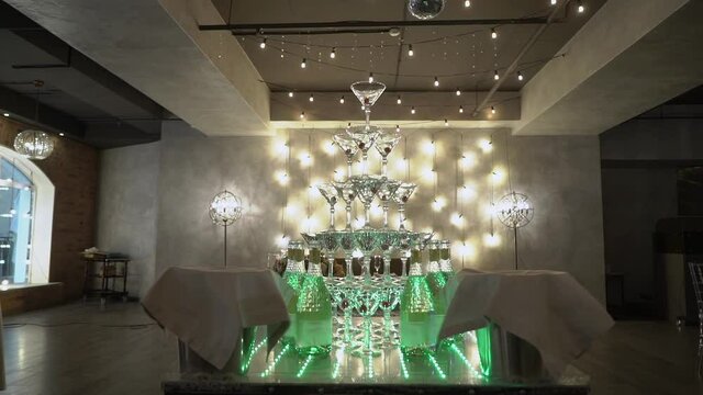 A pyramid of champagne glasses. Tower decorated with red cherry berries. Empty glasses for white sparkling wine at a restaurant party. Holiday, wedding, birthday, event.
