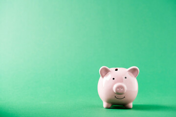 Pink piggy bank on green background. Finance, saving money concept. High quality photo