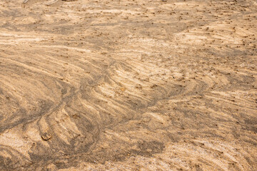 Amazing natural sand pattern made by wind and water on a sandy beach. Unique design for creative purpose. Design background. Random shapes on a dark and light sand surface