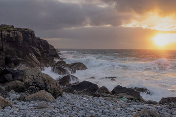 Rugged stone coast line and ocean waves at sunset. West of Ireland. Irish landscape. Dramatic sky. Sun flare. Irish landscape. Nature power and beauty concept