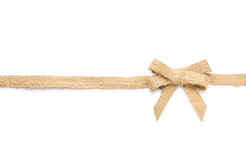 Fototapeta premium Burlap ribbon with pretty bow on white background, top view
