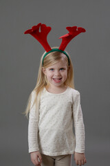 Studio portrait of adorable blonde toddler girl wearing reindeer headband. It's holiday Season!