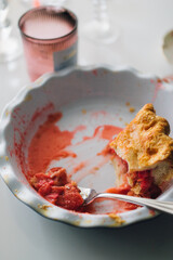 last slice of pink strawberry rhubarb pie in dish with fork