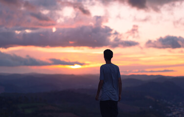Fototapeta premium silhouette of a young man with the clouds and sunset in the background.