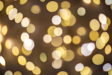 Blurred festive golden background with white round shiny lights on a dark background. Interesting...