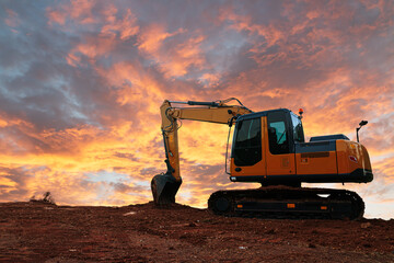 Yellow  Excavators are digging the soil in the construction site on the  cloud  sky background