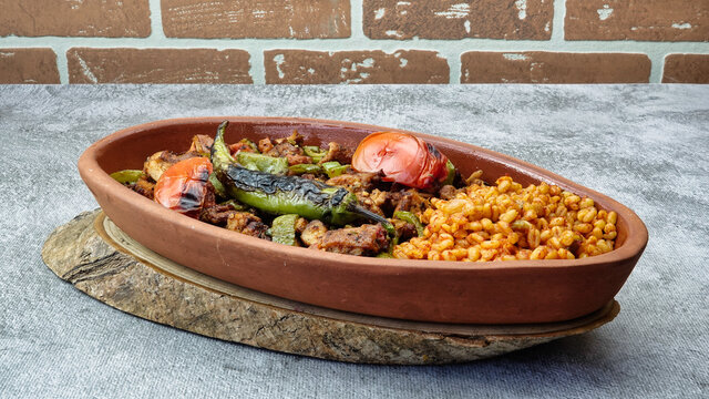 Close up of Turkish chicken Kebab called Mudurnu Kebab, garnished with vegetables, bulgur pilaf served on ceramic dish - Turkish, Food Kebab- Front of vintage birck wall	