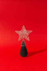 Christmas tree made of black ice cream cone with silver star bauble on top. Scarlet red colored background, close up perspective. Christmas and new year celebration concept.
