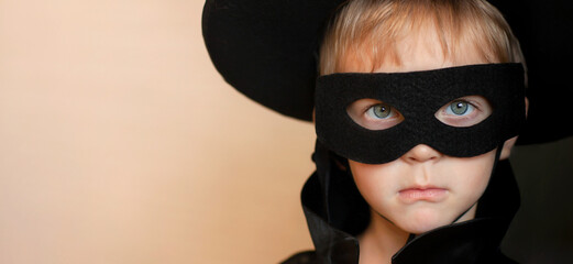 A serious boy in a mask and a black suit