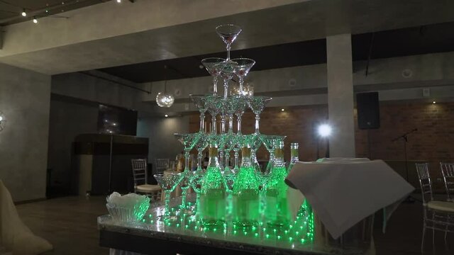 A pyramid of champagne glasses. Tower decorated with red cherry berries. Empty glasses for white sparkling wine at a restaurant party. Holiday, wedding, birthday, event.