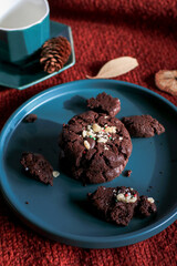 Chocolate Christmas Cookies on  green plate red background. Cozy home atmosphere. Festive homemade decorated sweets