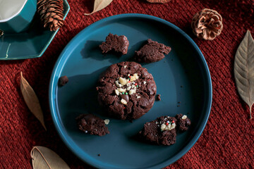 Chocolate Christmas Cookies on  green plate red background. Cozy home atmosphere. Festive homemade decorated sweets