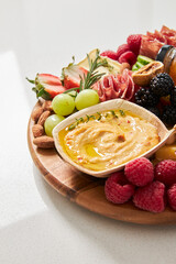 Cheese board with hummus, fruit and vegetables on a white background