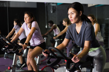Fototapeta na wymiar Woman ride stationary bike in a fitness club