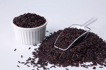 riceberry rice in a white bowl and a pile of rice on white background