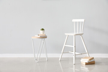 White chair and table with books near light wall