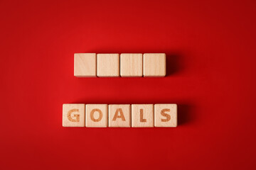 Wooden cubes and word GOALS on red background