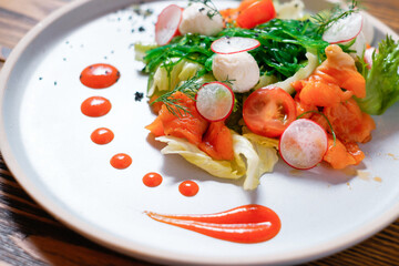 Vegetable salad with salmon, radish and tomatoes.
