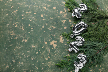 Silver balloons in shape of figure 2023 and fir tree branches on color background