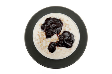Porridge with plum jam in the bowl isolated on the white background