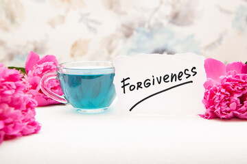 Forgiveness - text and pink peony flowers with blue tea, beautiful christian card