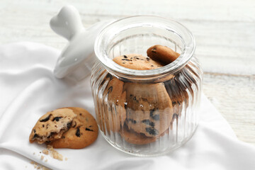 Obraz na płótnie Canvas Glass jar with tasty homemade cookies on light wooden background, closeup