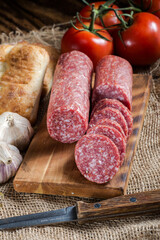 sliced salami  with bread and tomatoes on a rustic table