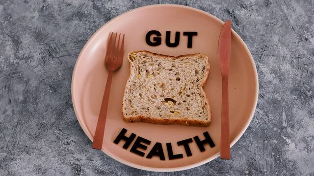 gut health text with wholegrain multiseeds slice of bread on dining plate with fork and knife, healthy nutrition research about the microbiome