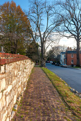 Fototapeta na wymiar old brick pavement along an old stone wall