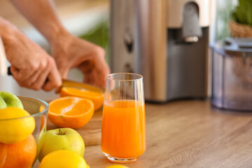 Glass of fresh orange juice on table in kitchen