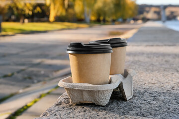 Takeaway cup of tasty latte on parapet outdoors