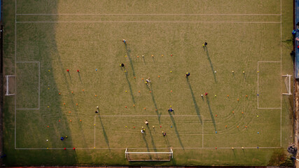 Aerial view showing kids playing soccer at field during sunset. Buenos Aires